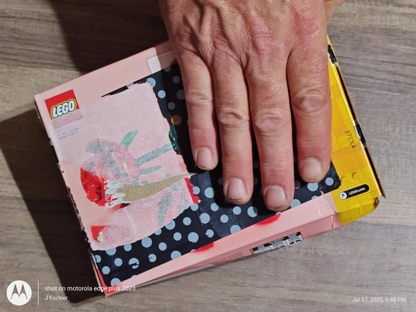 LEGO box with colorful design and hand resting on top.