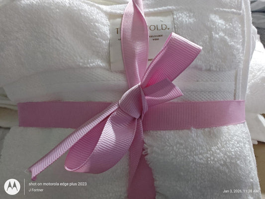 Luxury white bath towels set tied with a pink ribbon for elegant presentation.
