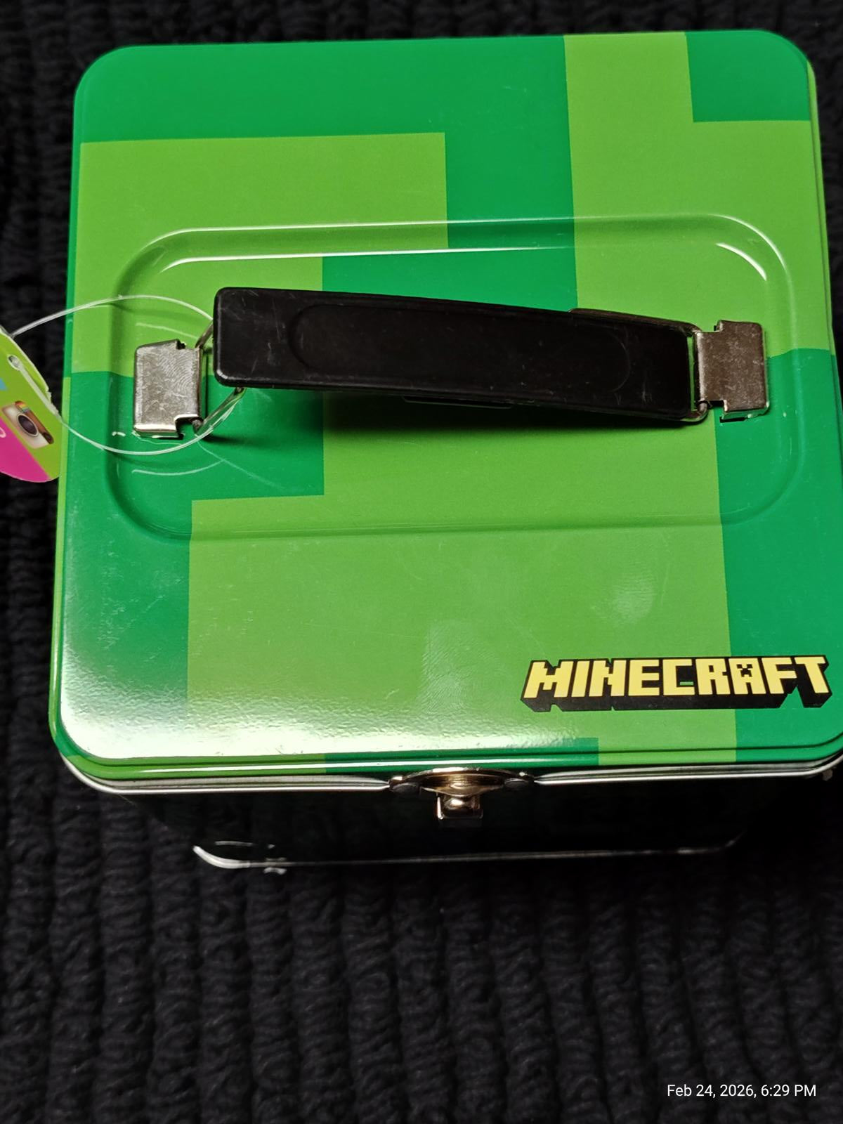 Minecraft lunchbox with a green pixelated design and black handle.