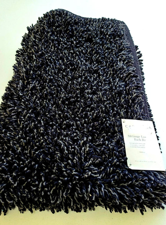 Black plush bath rug with soft texture and tag visible.