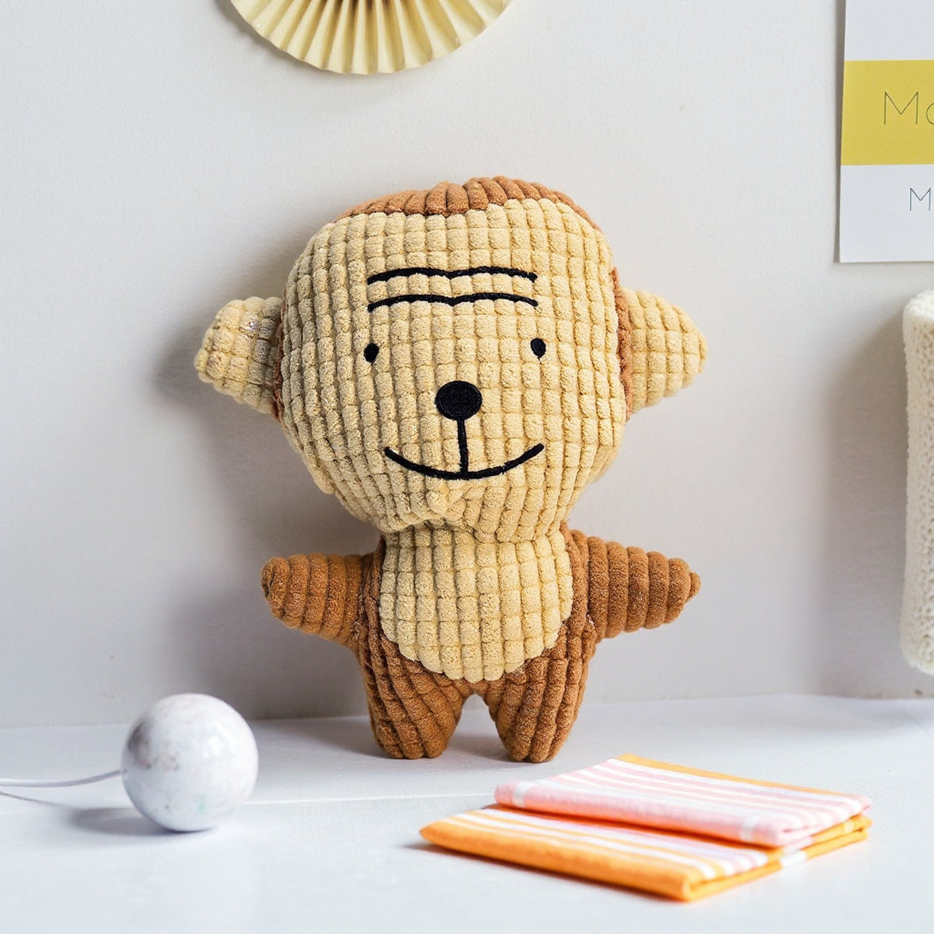 Monkey plush toy with textured fabric, smiling face and arms outstretched.