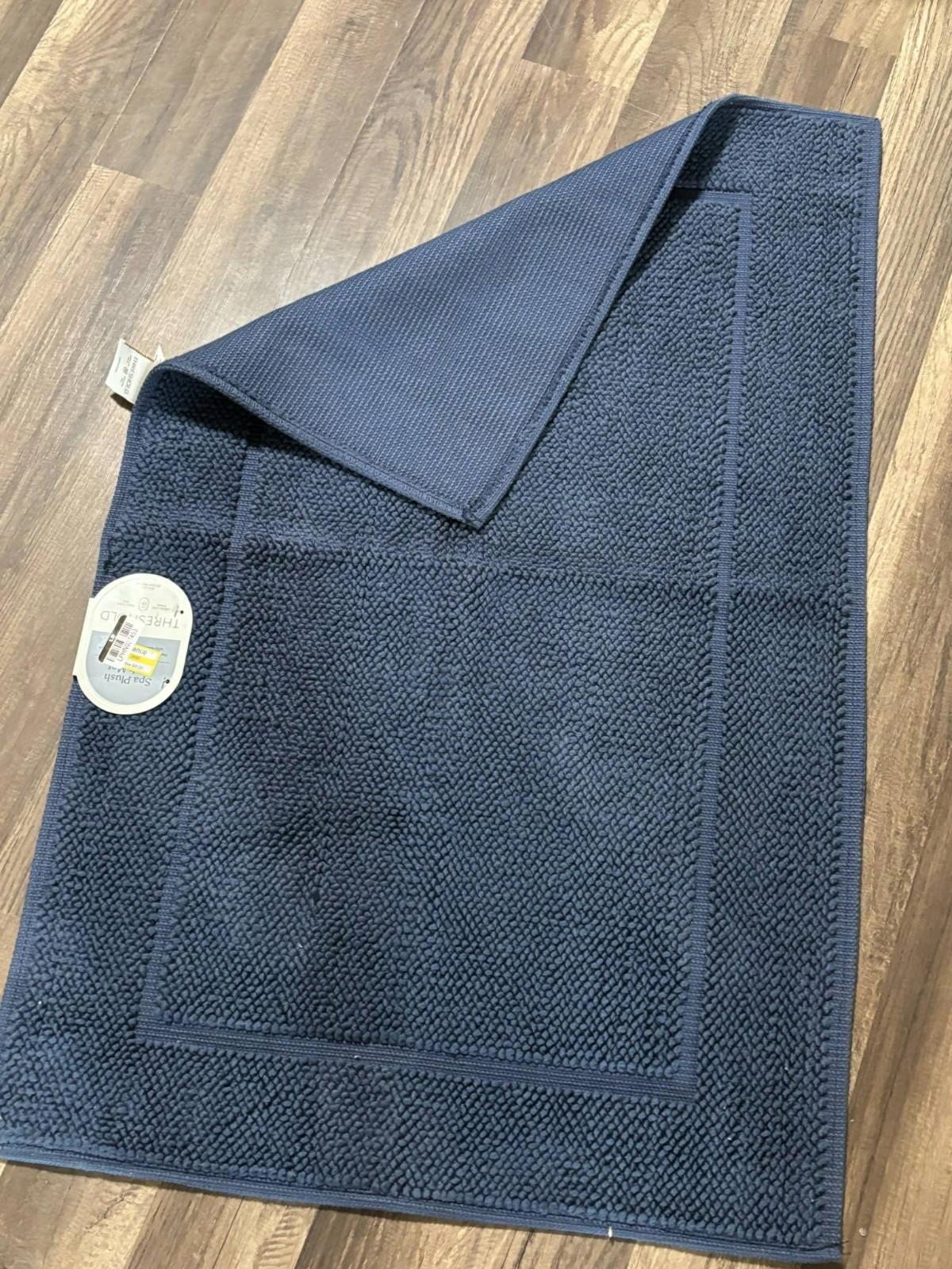 Navy bath mat featuring a textured surface and a soft underside for comfort.