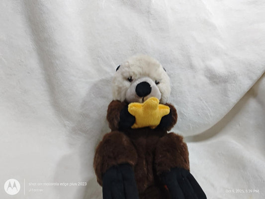 Otter plush toy holding a yellow star, soft and cuddly design.