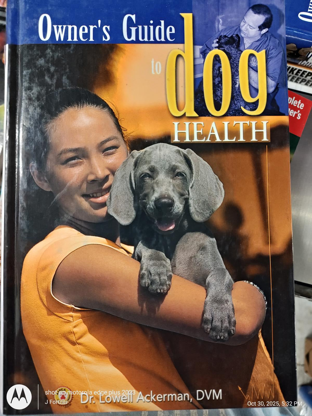 Owner's Guide to Dog Health featuring a woman holding a gray puppy, providing essential pet care tips.