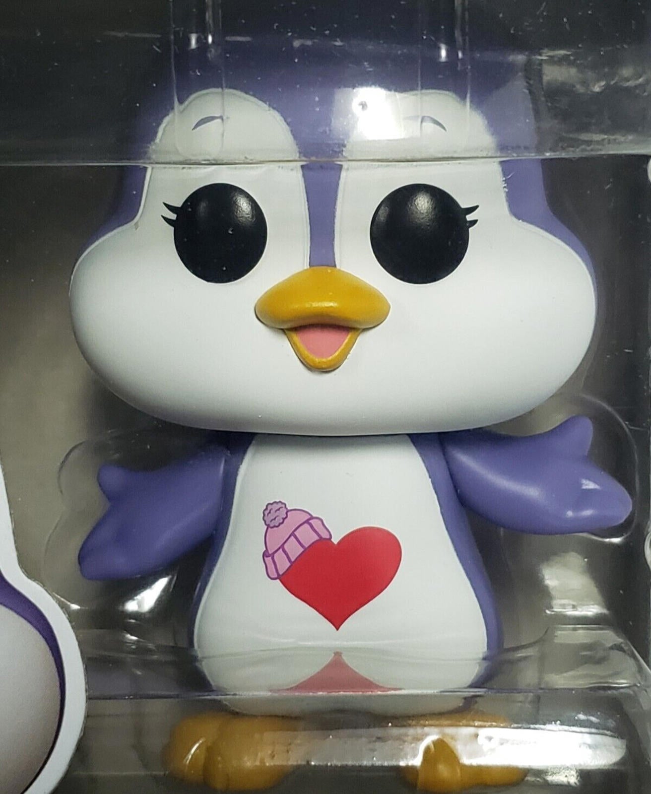 Penguin plush toy with a heart design and purple accents, wearing a pink hat.