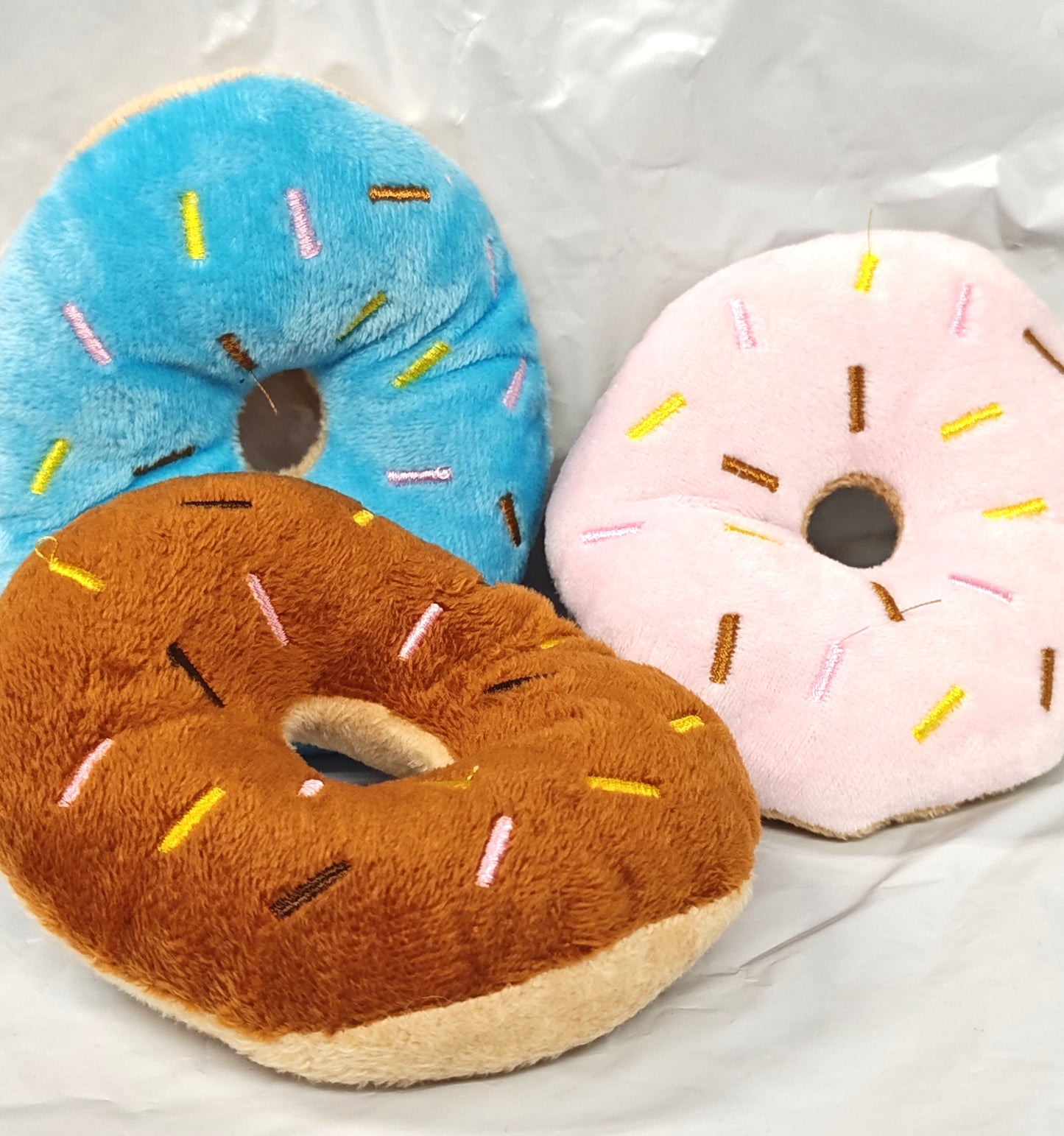 Plush donut set featuring blue, pink, and brown colors with colorful sprinkles.