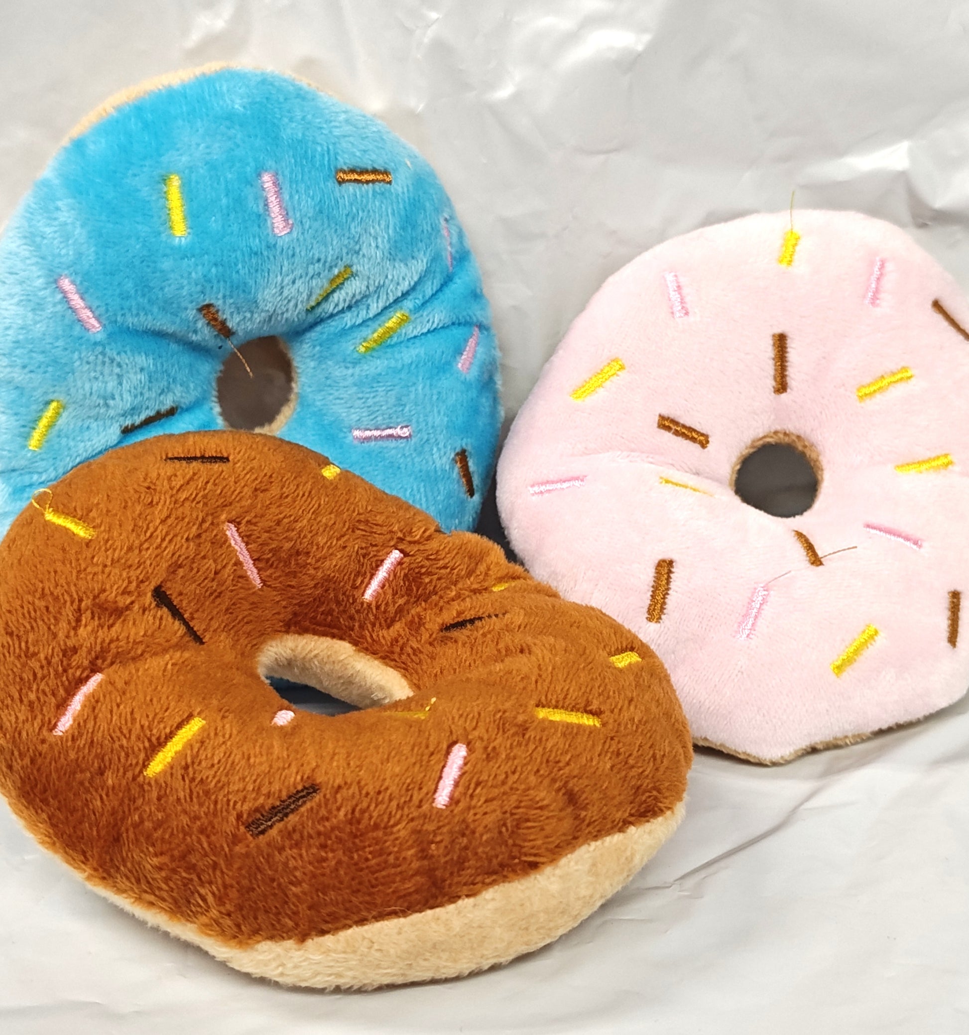 Plush donut set featuring blue, pink, and brown colors with colorful sprinkles.