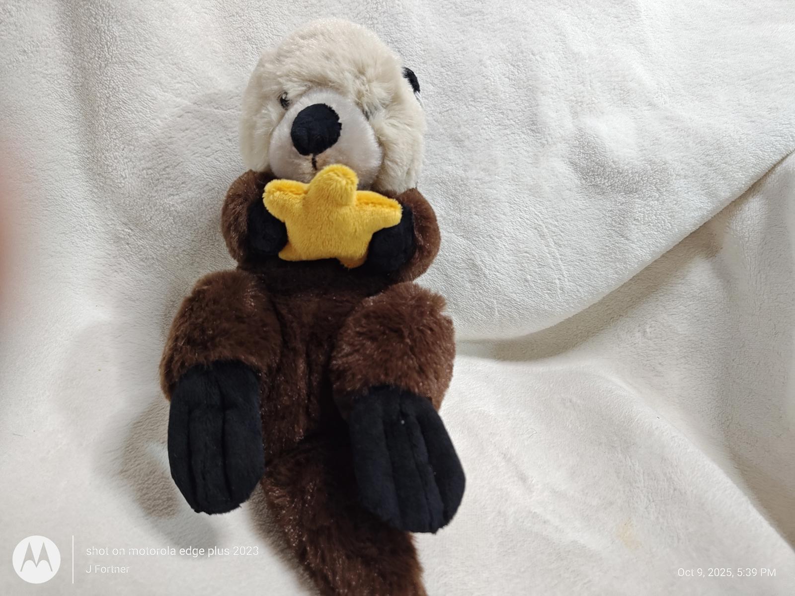 Otter plush toy holding a yellow star, soft and cuddly design.