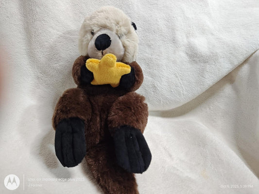 Otter plush toy holding a yellow star, soft and cuddly design.