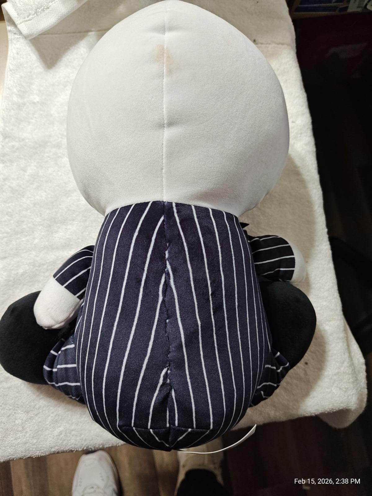 Plush toy in a pinstripe suit, featuring a round head and black limbs.