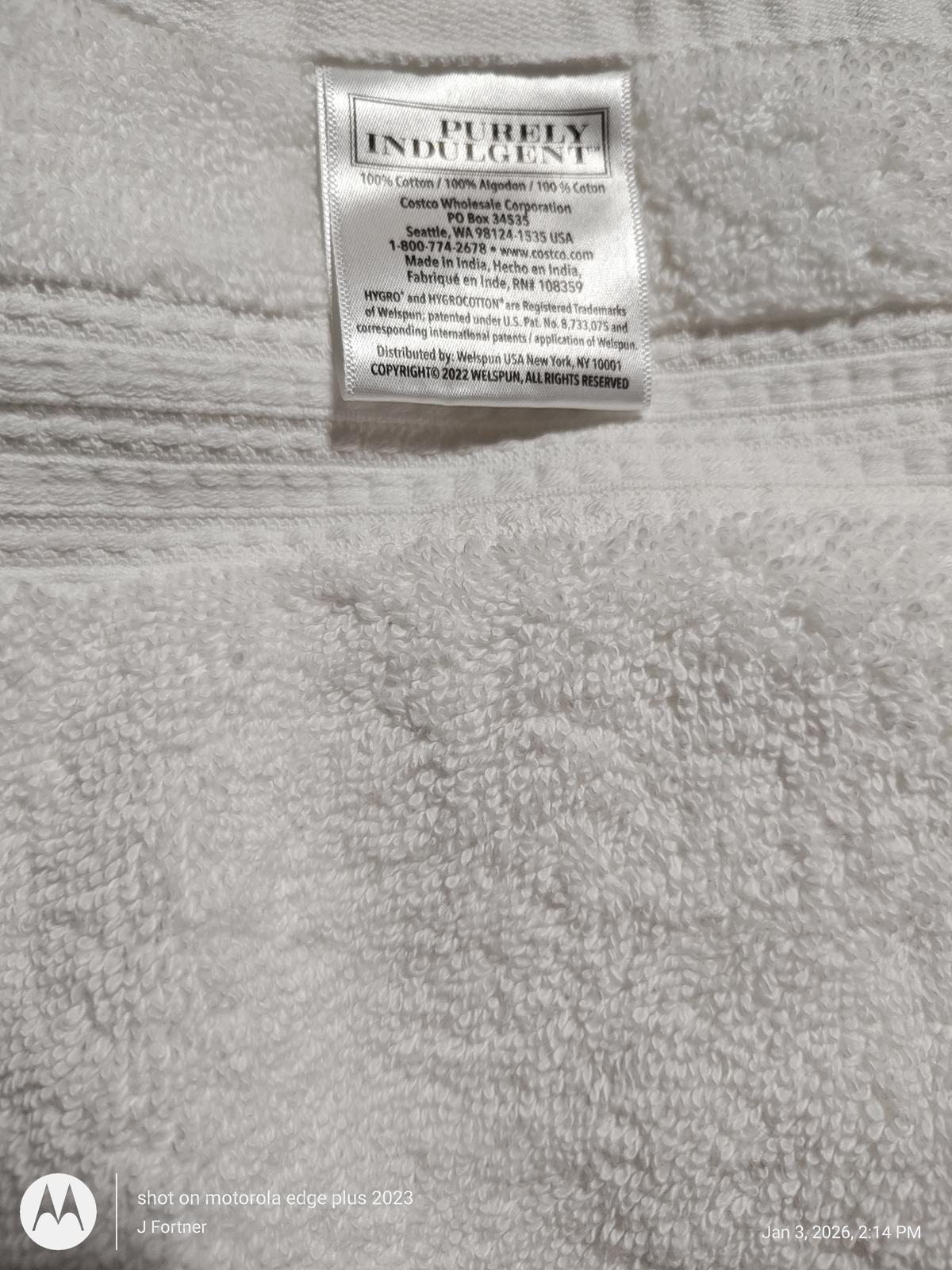 Purity Indulgence white bath towel with soft texture and care label.