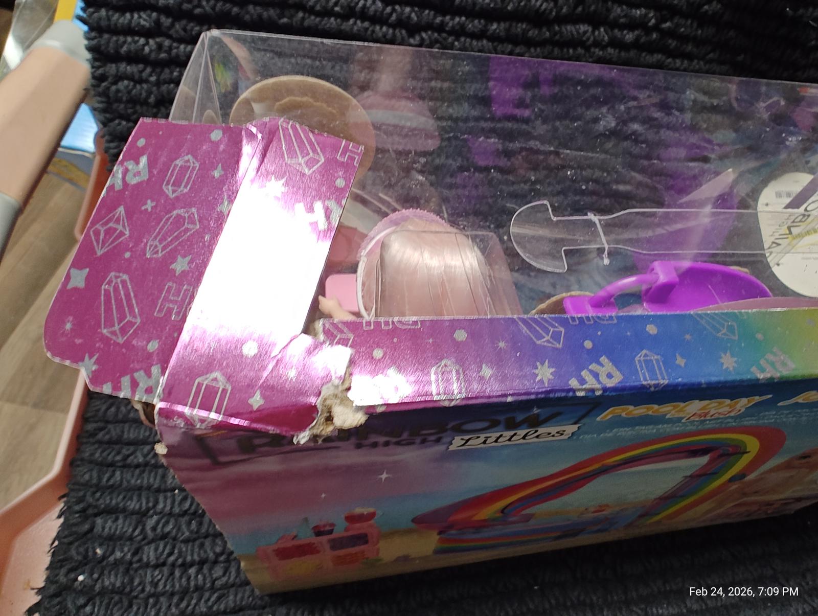 Rainbow Surprise Doll packaging with colorful design and visible damage.