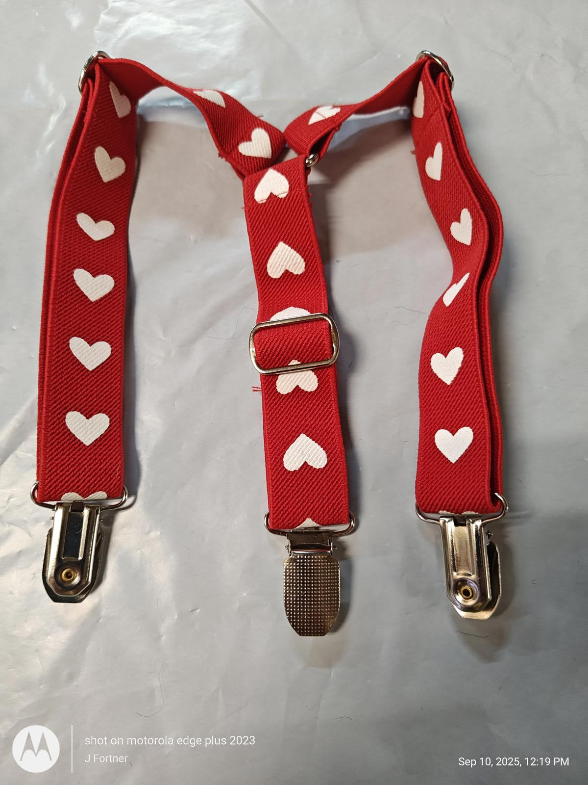 Red heart-patterned suspenders with silver clips for secure fastening.
