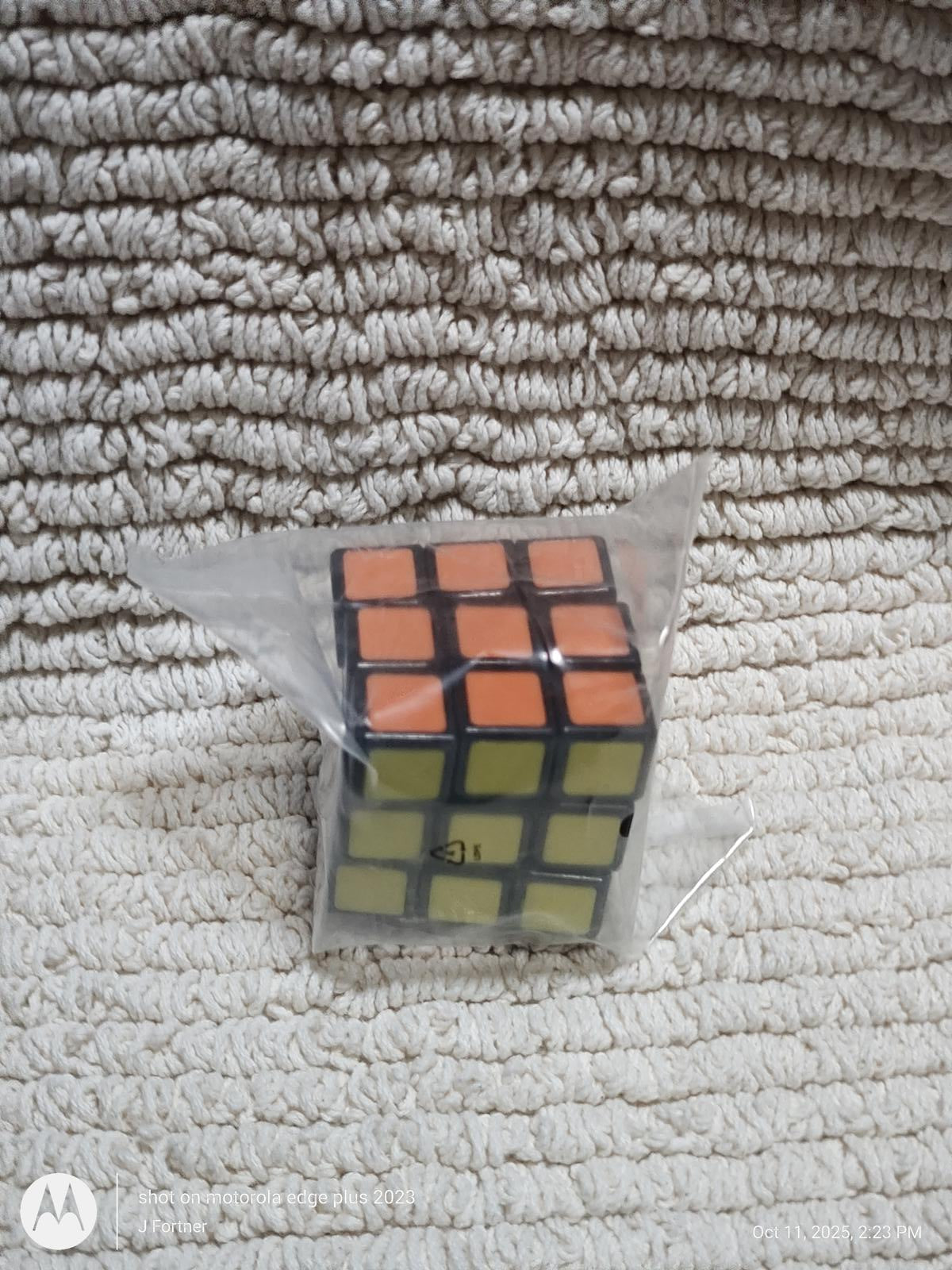 Rubik's Cube in packaging with orange and green stickers visible.