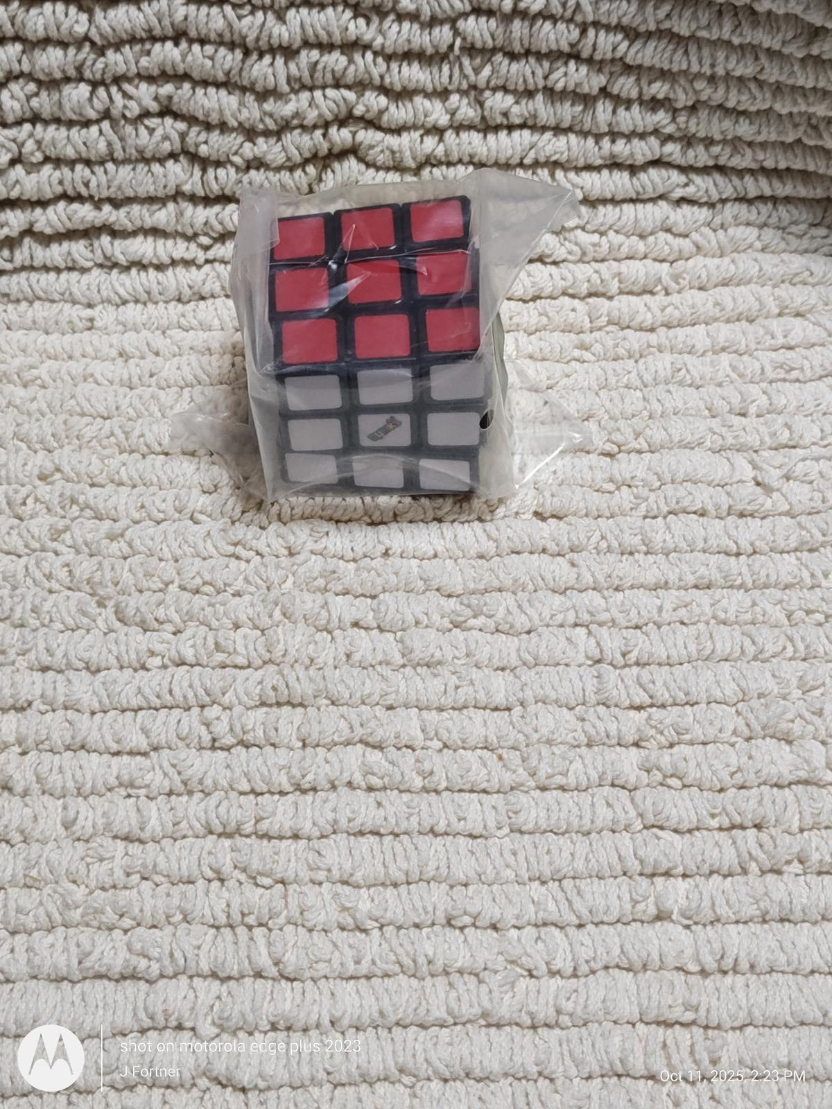 Rubik's Cube featuring red and black squares on a textured surface.