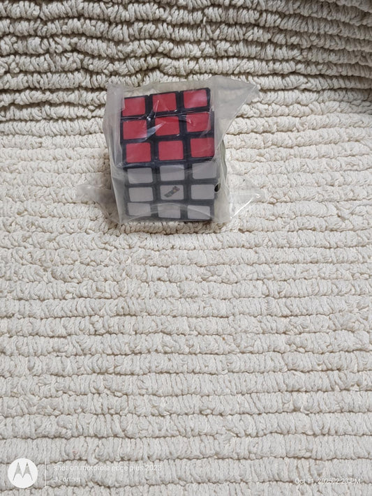 Rubik's Cube featuring red and black squares on a textured surface.