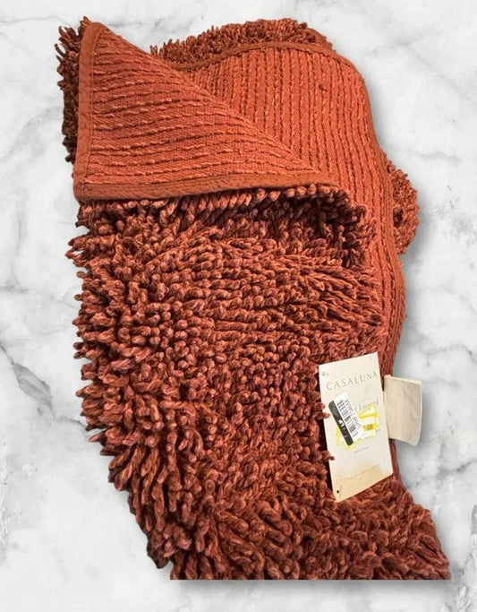 Rust Orange Plush Bath Mat with textured surface and tag.