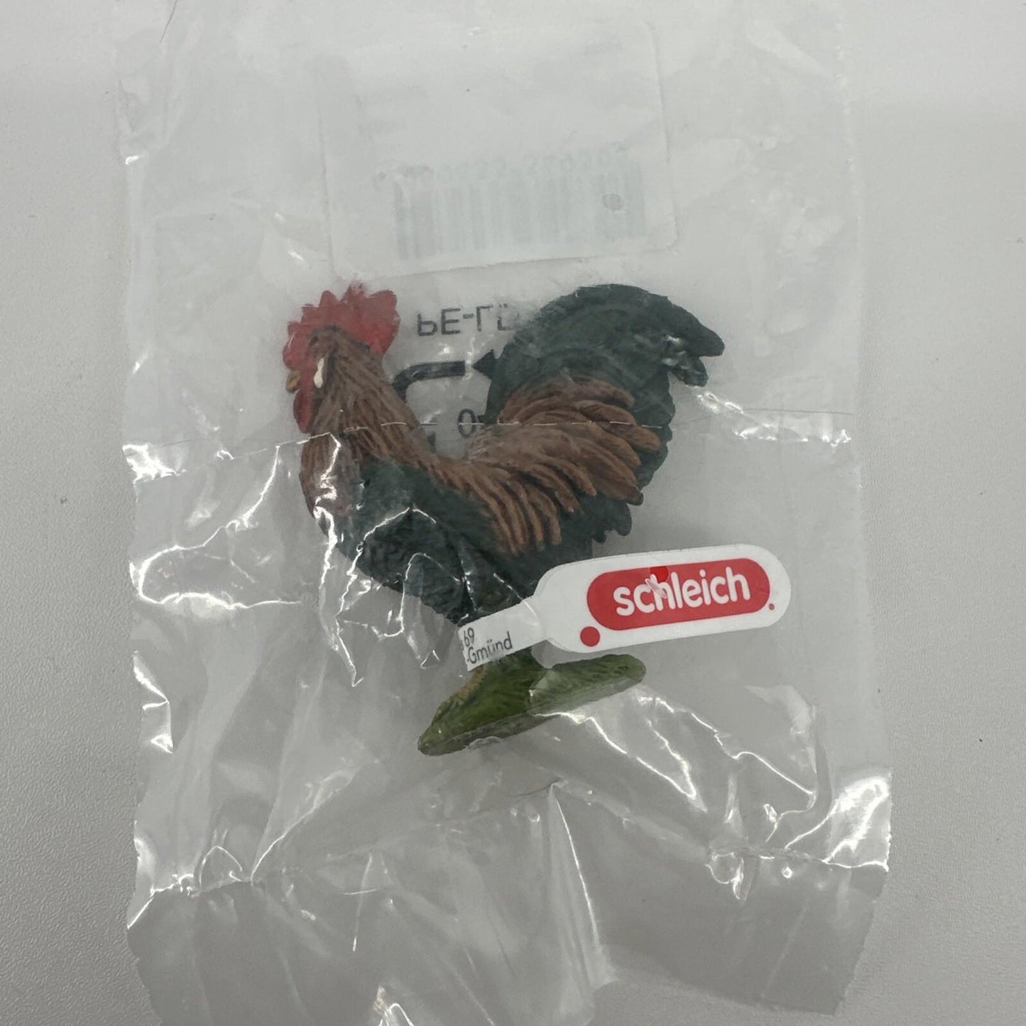 Schleich rooster figurine in packaging, featuring detailed feathers and vibrant colors.