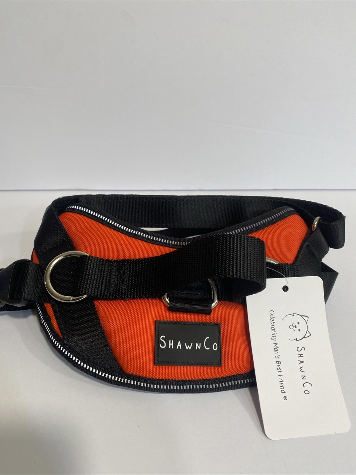 ShawnCo orange pet harness with black straps and logo tag.