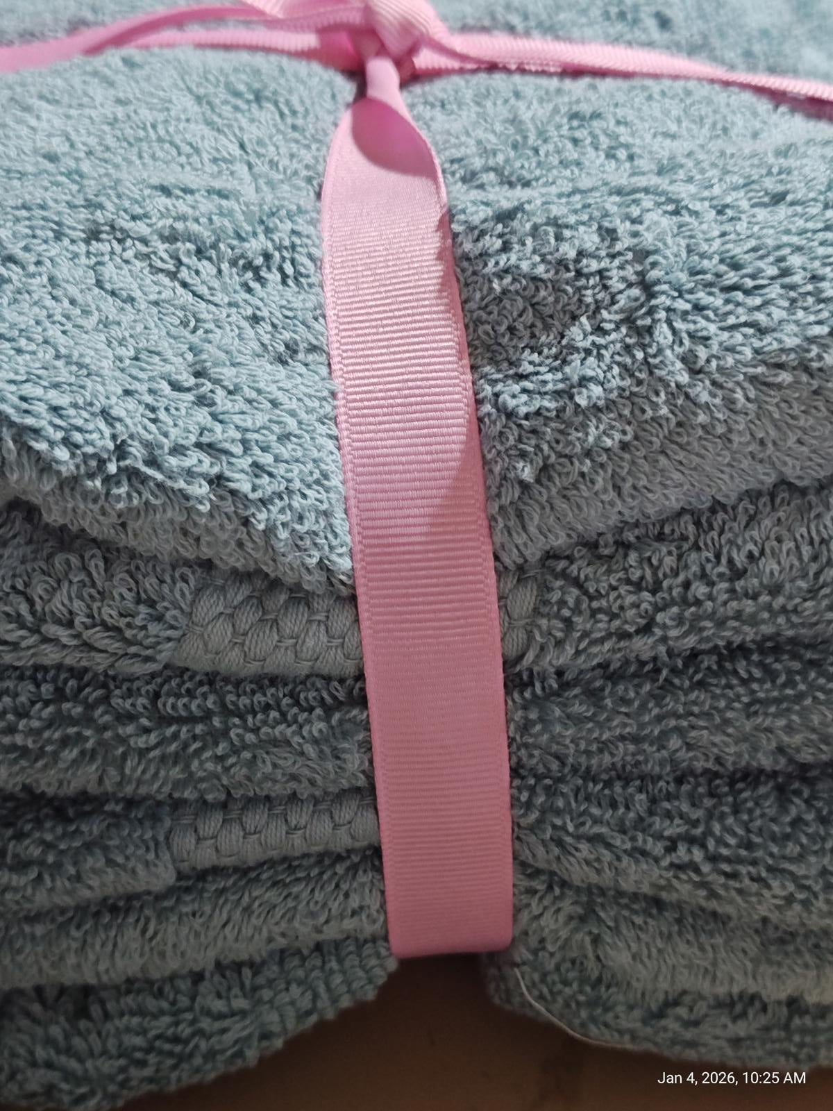 Soft blue bath towels neatly stacked and tied with a pink ribbon.