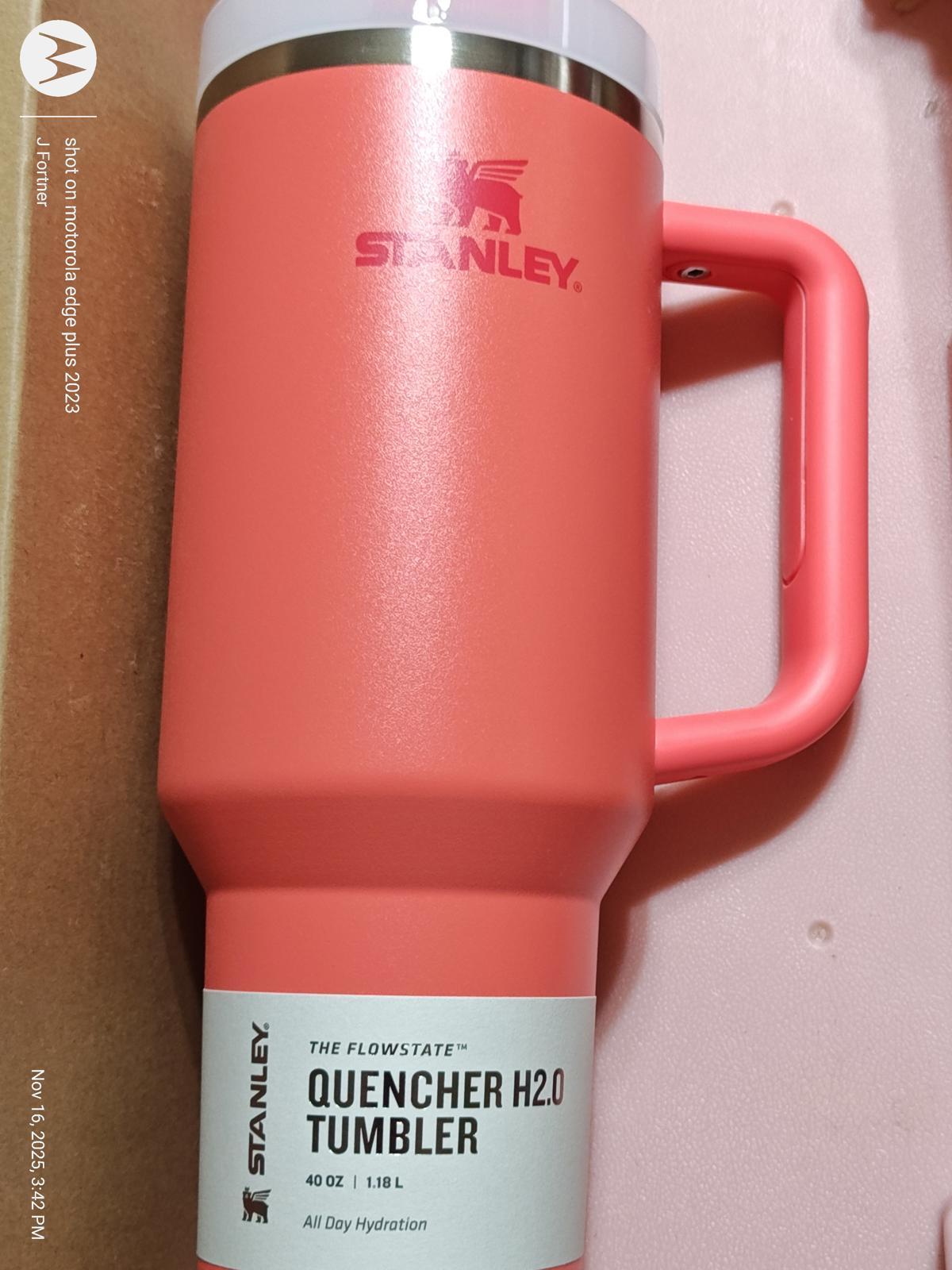 Stanley Quencher H2.0 Tumbler in coral color with a sturdy handle for easy grip.