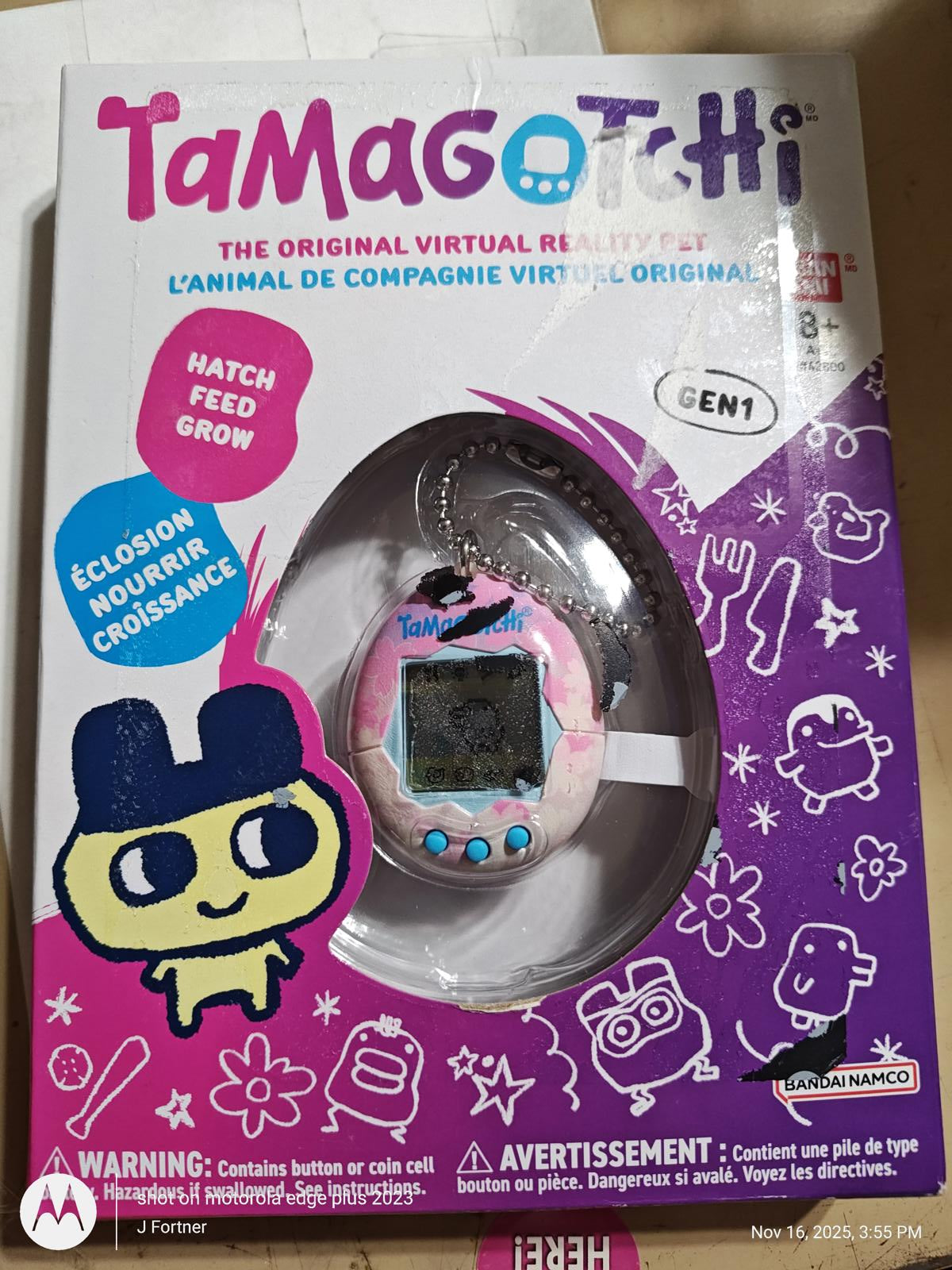 Tamagotchi virtual pet in pink packaging with character design and accessories.