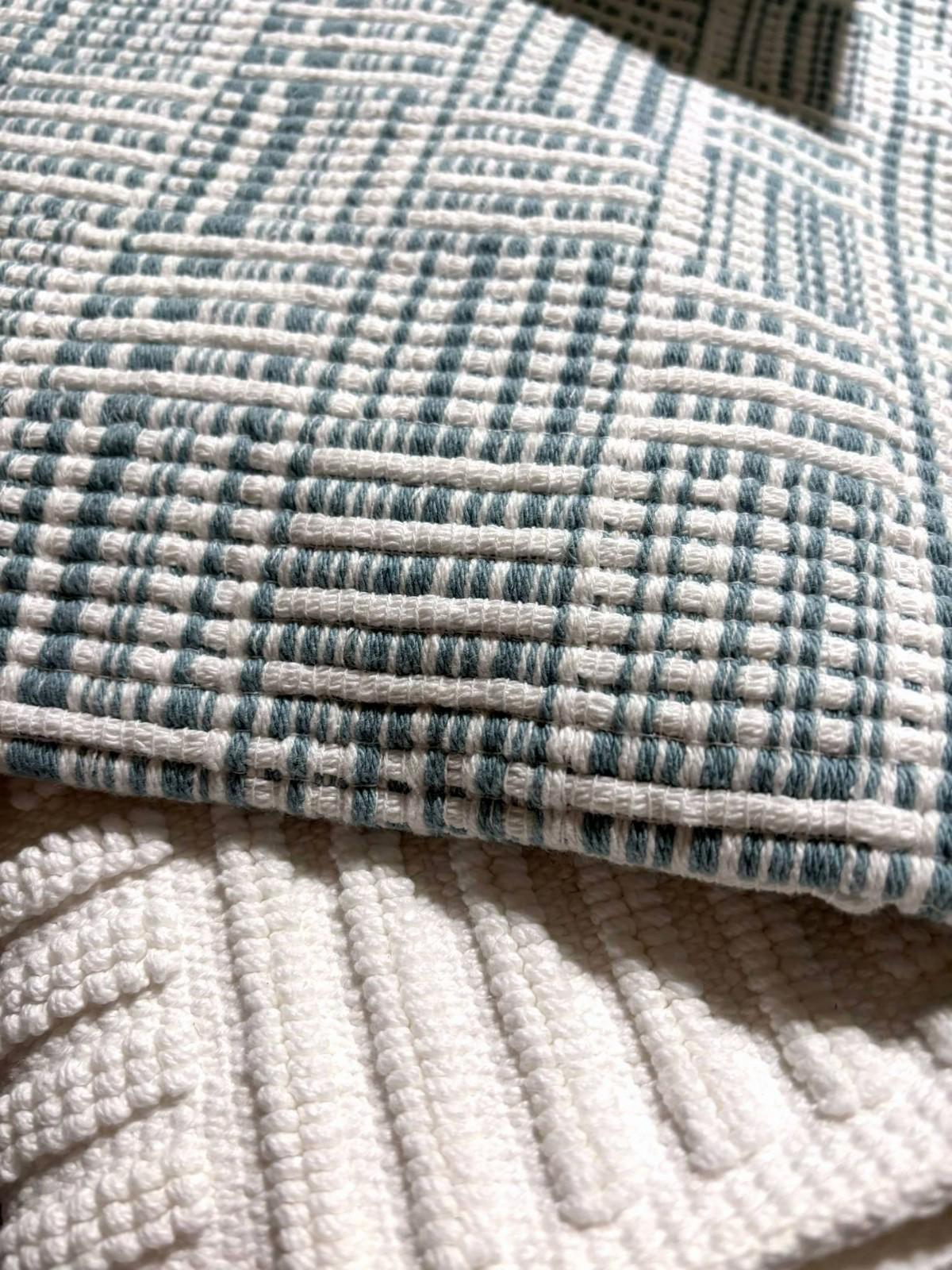 Textured cotton throw blanket featuring a blue and white woven pattern.