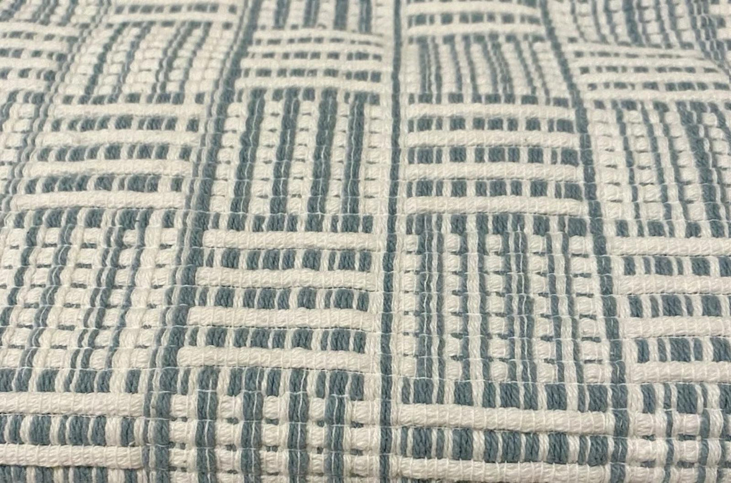Textured fabric with a geometric pattern in blue and cream colors.