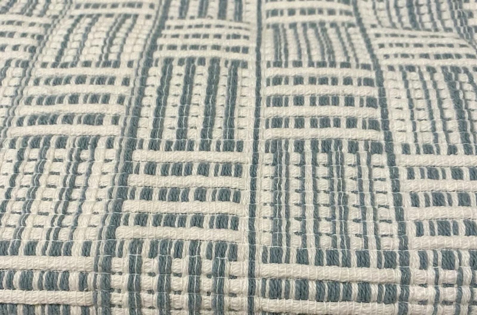 Textured fabric with a geometric pattern in blue and cream colors.