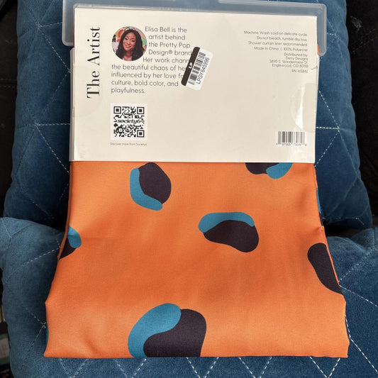 The Artist fabric featuring an orange background with abstract blue and black shapes.
