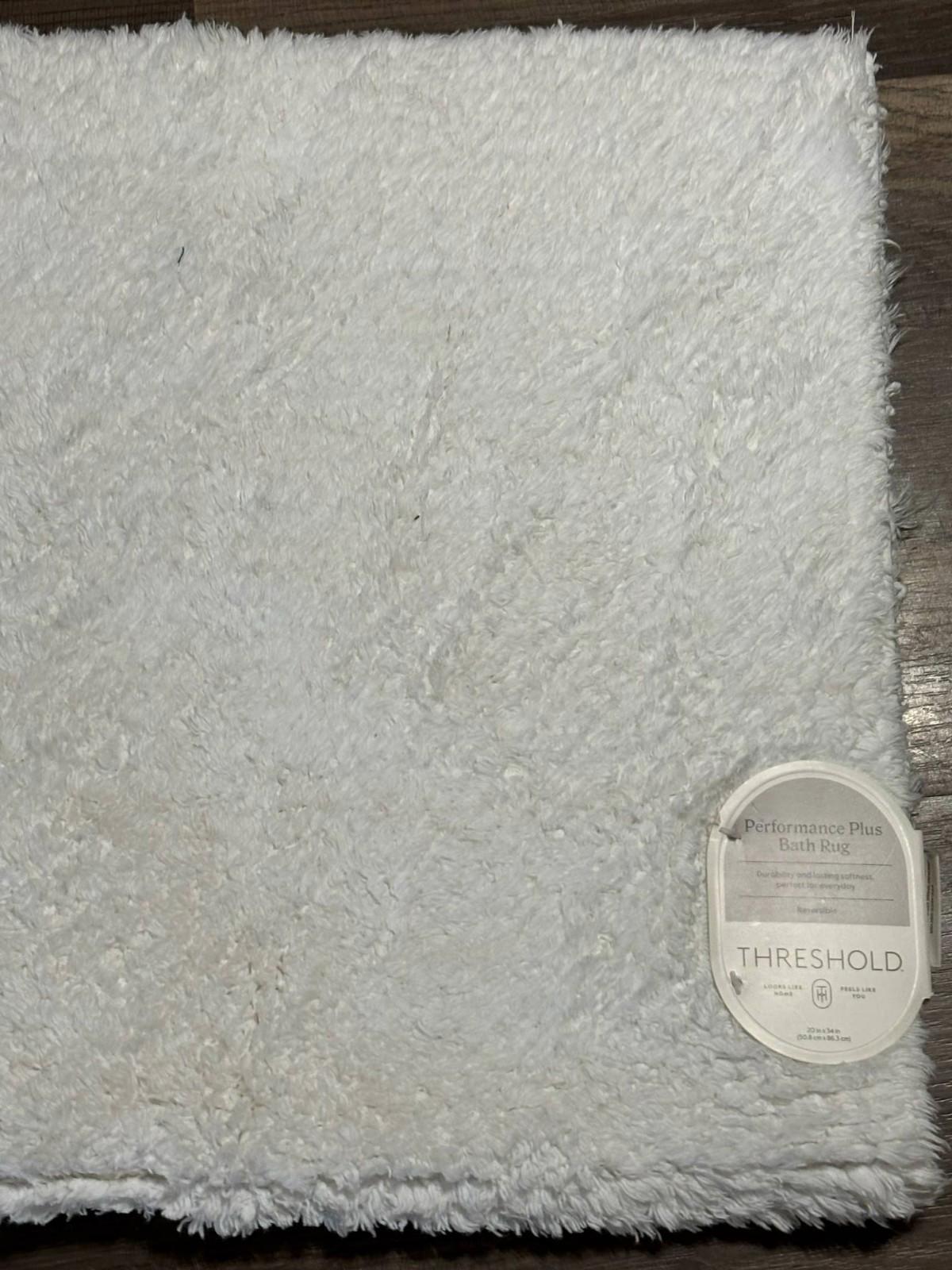 Threshold white plush bath mat with soft texture and label.