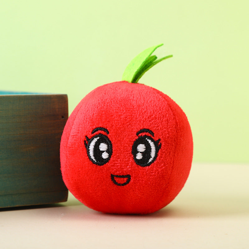 Tomato plush toy with a smiling face and green leaf on top.