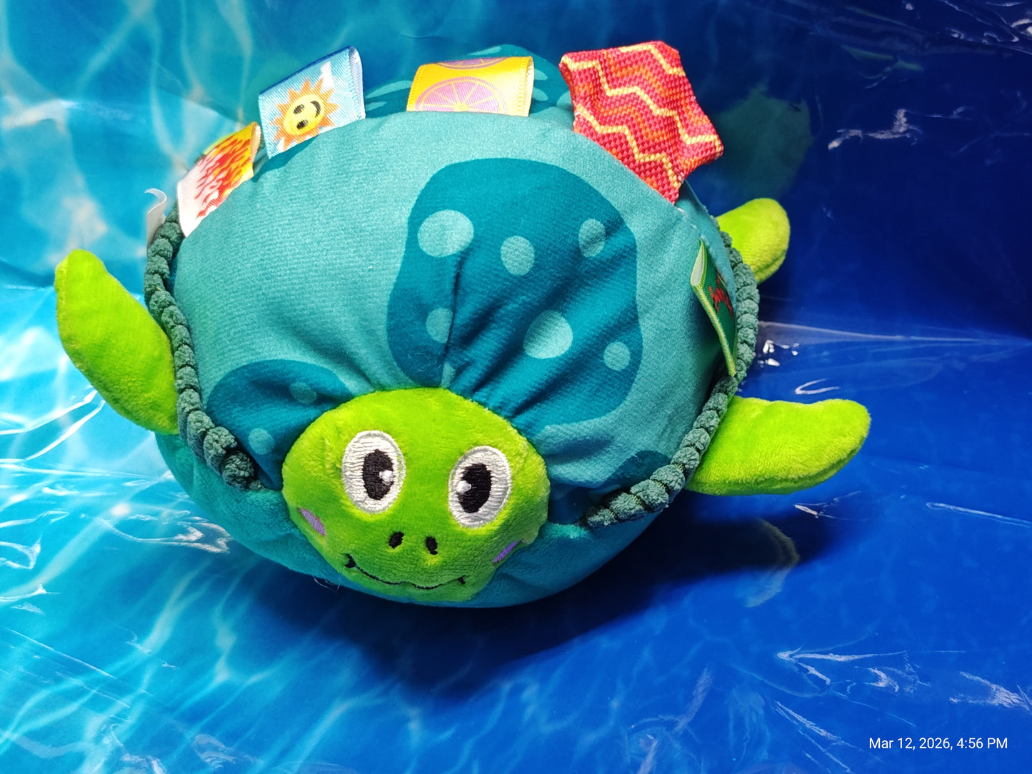 Turtle plush toy with colorful tags and a soft, green exterior, perfect for infants.