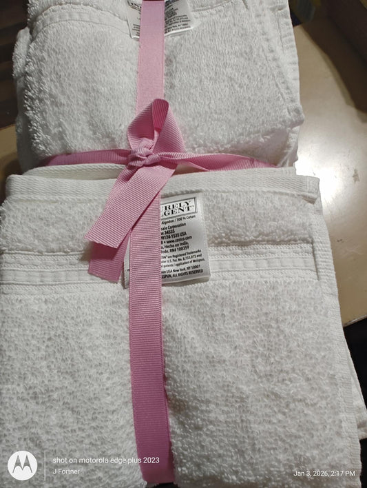 White bath towels neatly folded and tied with a pink ribbon.
