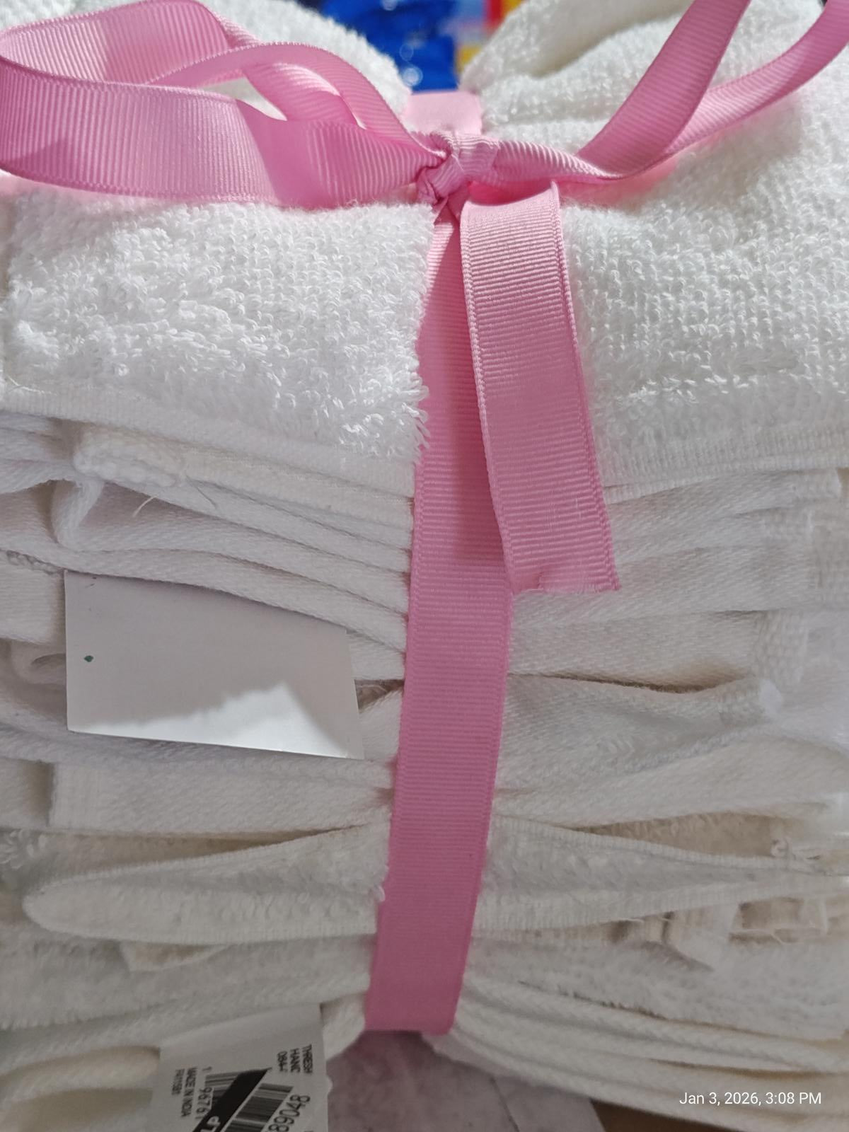 White bath towels neatly stacked and tied with a pink ribbon.
