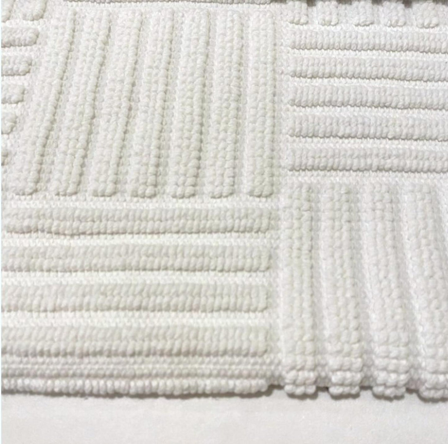 White cotton bath mat featuring textured patterns and a soft surface.