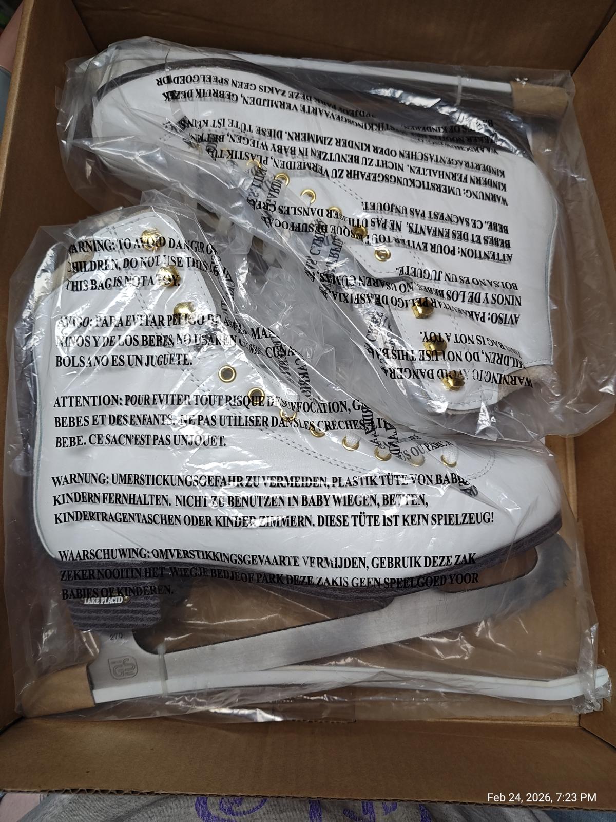 White high-top sneakers with gold eyelets, packaged in a box.