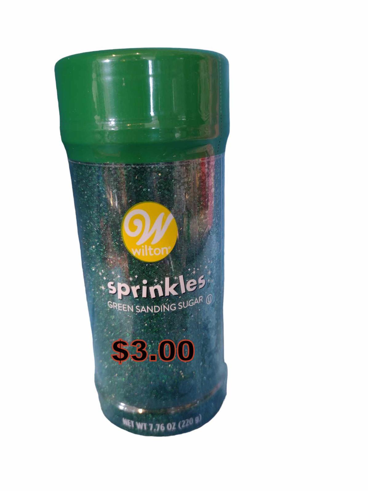 Wilton sprinkles green sanding sugar in a clear container with a green lid.