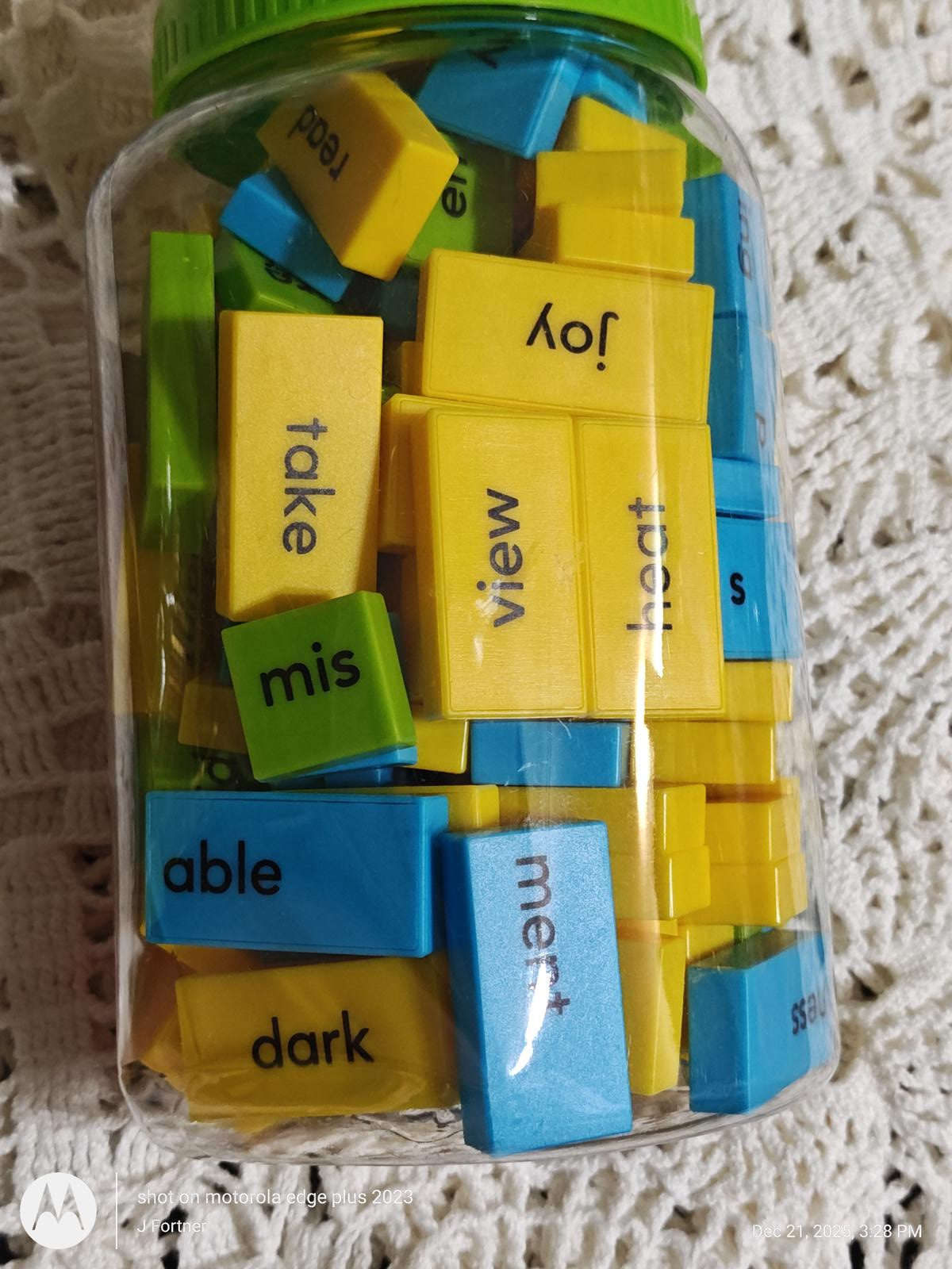 Word building blocks set in a jar featuring colorful blue, yellow, and green pieces for educational play.