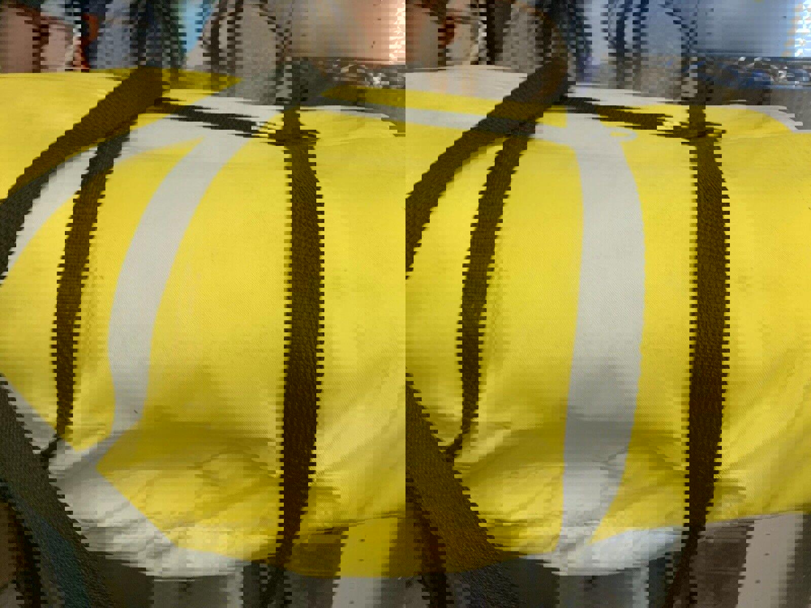 Yellow camping tarp with black straps, ideal for outdoor activities.