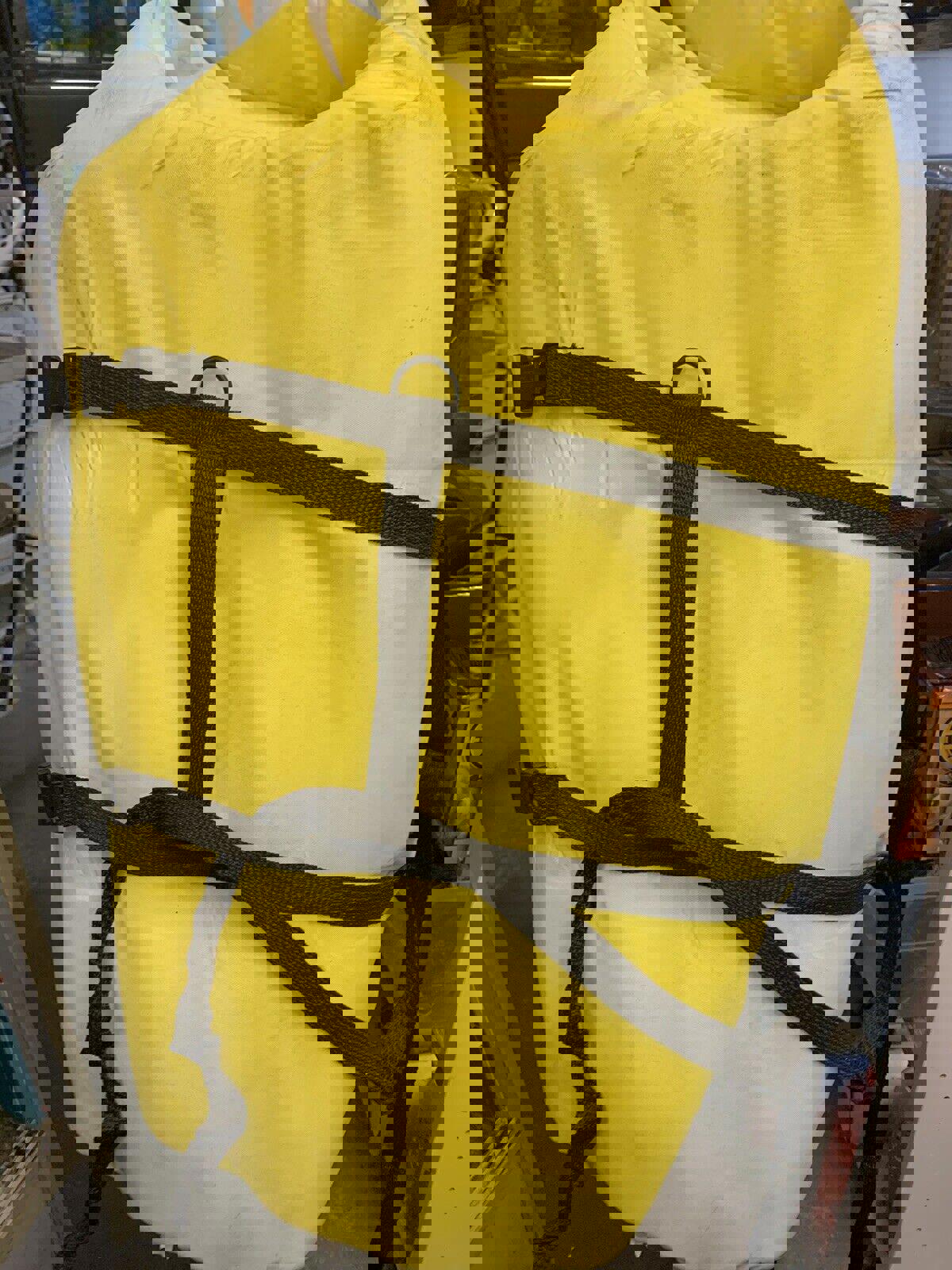 Yellow waterproof dry bag with black straps for outdoor adventures.