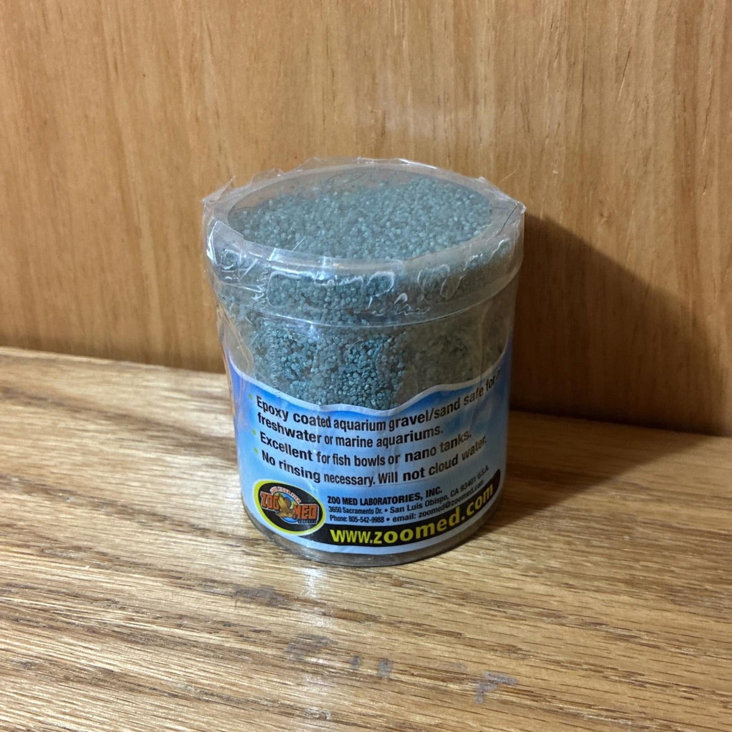 Zoo Med Reptile Sand is a natural substrate for reptiles, featuring fine, gray grains in a clear container.